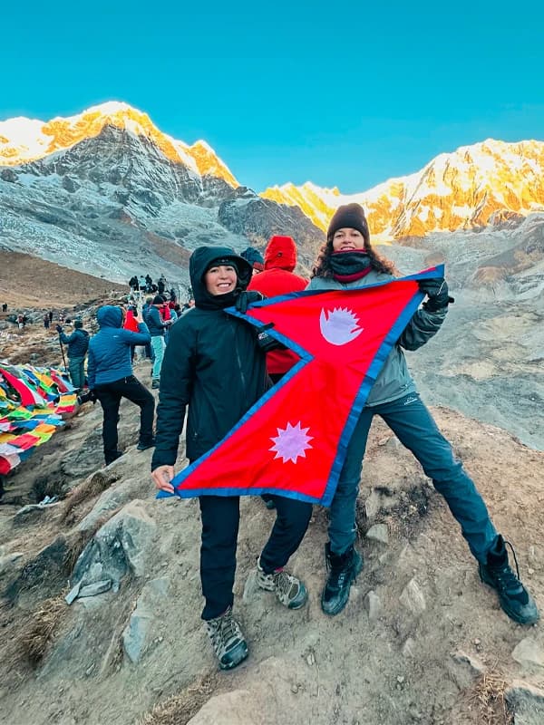 Trekkers holding flag of Nepal at Annapurna Base Camp