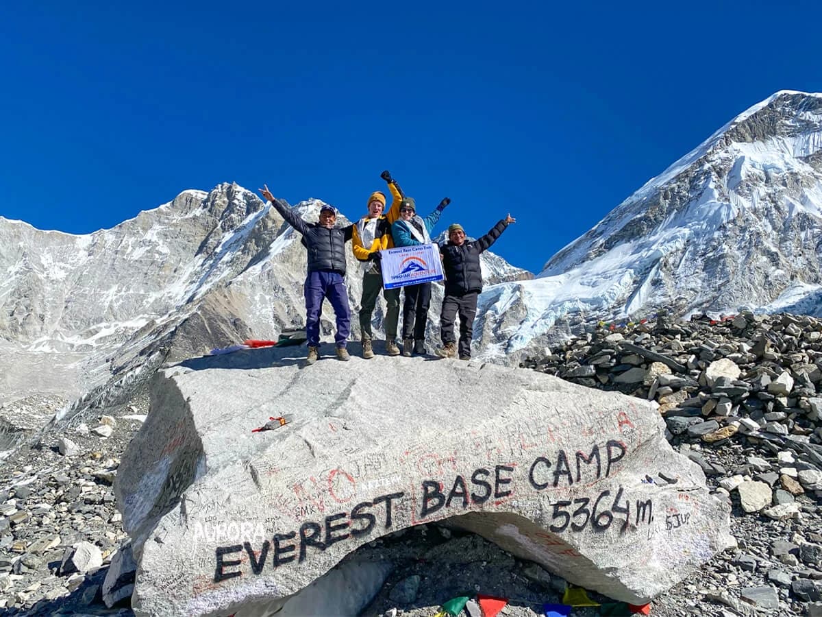 Trekkers sitting on the iconic rock at Everest Base Camp
